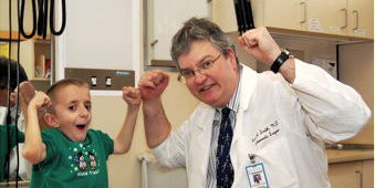 Photograph of a young boy and his doctor flexing their biceps. 